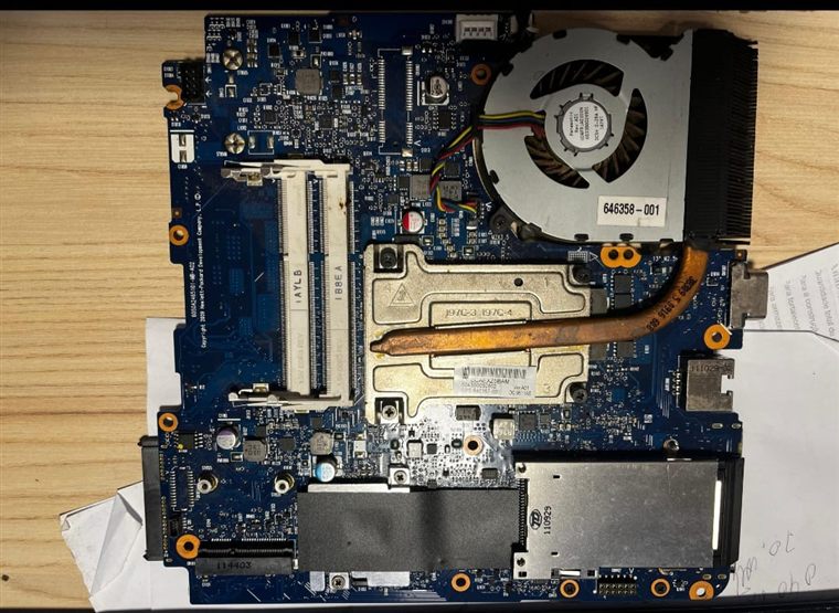 Placa-mãe de notebook aberta para reparo, com cooler e dissipador